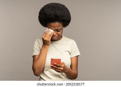 Young Woman Cry Reading Sms On Smartphone. Unhappy Black Female Getting Bad News In Mobile Phone Message Notification Sobbing And Wiping Tears With Napkin. Life Troubles, Crisis And Breakup Concept