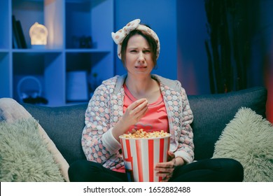 Junge Frau weint, während sie sich einen sehr bewegenden Film mit Popcorn nachts anschaut.