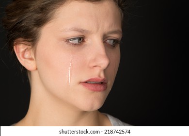Young woman crying on a black background.