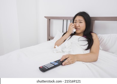 Young Woman Crying While Watching TV In Bed