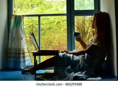 Young Woman With Cup Of Tea On The Window Sill In Rainy Weather.