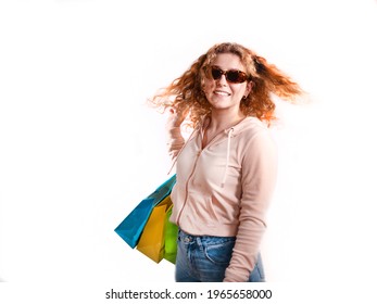 Young woman with curly flying hair, carries blue and yellow shopping bags.