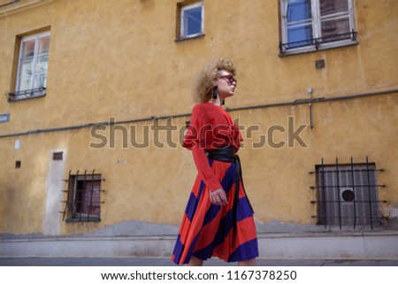 Young woman with curly hair in red retro dress. Walk around the city