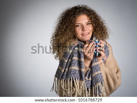 Young woman with curly hair, A woman in a scarf is frozen drinking hot tea
