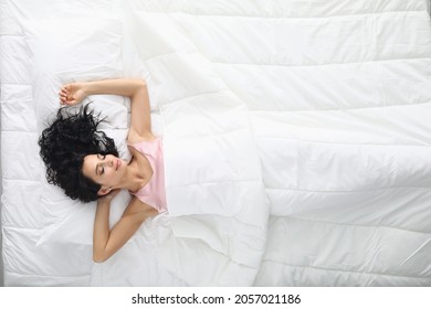 Young woman with curly hair sleeping in white bed top view - Shutterstock ID 2057021186