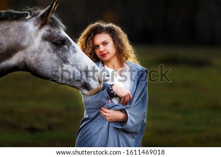 Young woman curly hair with a white horse and white cat in the field