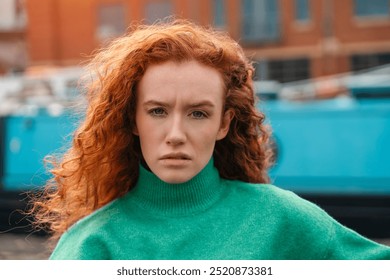 Young Woman With Curly Red Hair Wears Green Sweater by Serene Waterfront During Daylight - Powered by Shutterstock