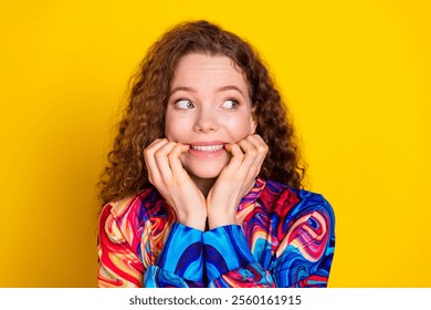 Young woman with curly red hair in a colorful pullover smiles joyfully against bright yellow background. - Powered by Shutterstock