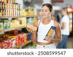 Young woman customer chooses pasta in grocery store