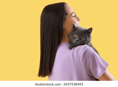 Young woman with cute British Shorthair cat on yellow background, closeup - Powered by Shutterstock