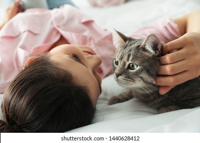 Young Woman With Cute Cat On Bed. Pet And Owner