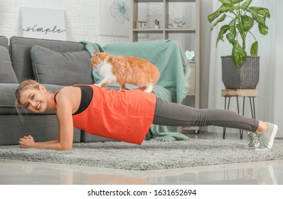 Young Woman With Cute Cat Practicing Yoga At Home