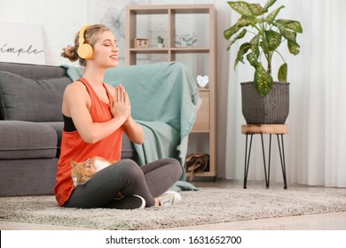 Young Woman With Cute Cat Practicing Yoga At Home