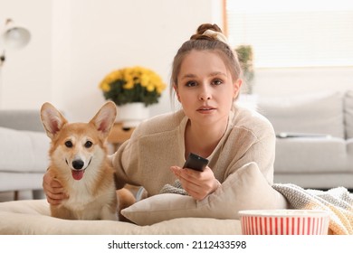 Young Woman With Cute Corgi Dog Watching TV At Home