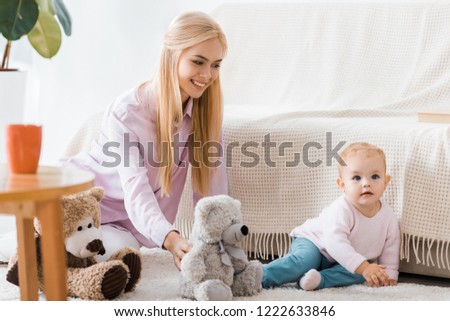 young woman with cute daughter playing toys on carpet
