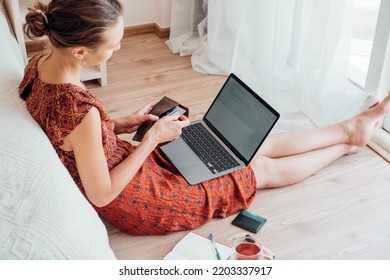 Young Woman In Cute Dress Choosing Credit Card For Online Shopping. Girl Using Computer Buying Gifts Online. 