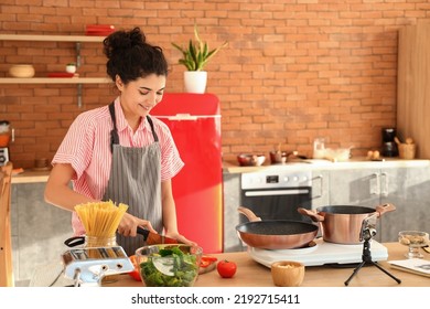 Young Woman Cutting Avocado While Following Video Tutorial In Kitchen