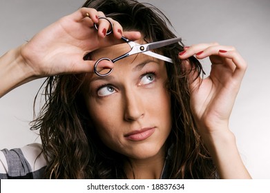 Young Woman Cutting Her Fringe Over Grey Background