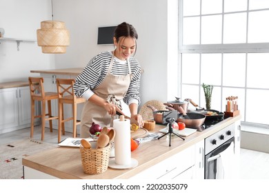 Young Woman Cutting Lemon While Following Cooking Video Tutorial In Kitchen