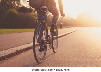 A young woman is cycling into the sunset in the park