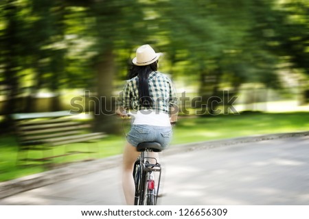 Young woman cycling through the park