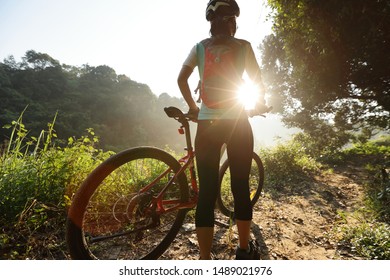 Young woman cyclist  enjoy the beautiful sunrise on summer rainforest trail - Shutterstock ID 1489021976