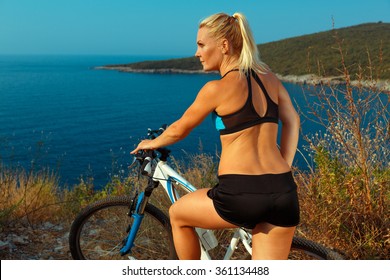 Young Woman Cyclist On A Mountain Bike Looking At The Landscape Of Mountains And Sea