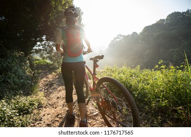 Young woman cyclist riding mountain bike on summer forest trail  - Shutterstock ID 1176717565