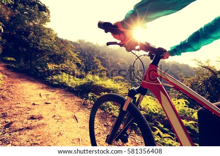 young woman cyclist riding mountain bike on forest trail