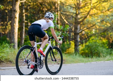 Young Woman Cyclist Riding Road Bicycle on Free Road in the Forest at Hot Summer Day. Healthy Lifestyle Concept. - Powered by Shutterstock