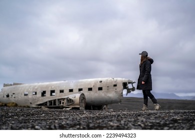 young woman at damaged dc 3 plane in iceland black beach