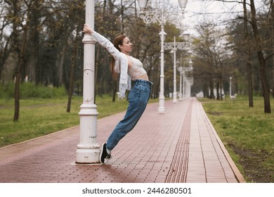 Young woman dancing around the light pole outdoors in the park, in rainy weather. Contemporary ballet dancer. - Powered by Shutterstock