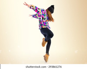 Νεαρή γυναίκα χορεύει χορό του δρόμου πάνω από ώχρα φόντο