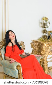 Young Woman With Dark Hair In A Long Red Dress In A Baroque, Renaissance Or Rococo Living Room. In A Luxurious Interior