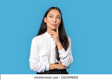 Young Woman With Dark Long Hair Wearing White Shirt And Black Skirt Standing Isolated On Blue Background Touching Face Looking Up Thinking Of Solution