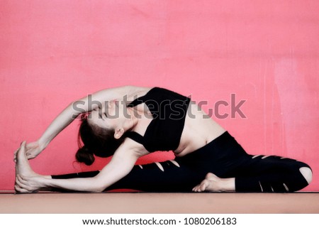 Young woman in dark sportswear doing twine  for strength her legs