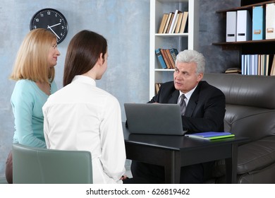 Young Woman And Daughter Meeting With Teacher At School