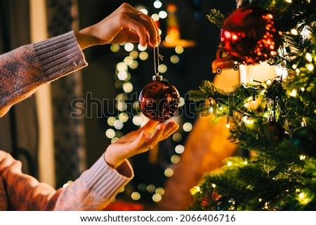 Young woman decorates the Christmas tree with toys. Preparing for the holidays