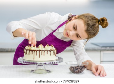 Young Woman Decorating Chocolate Cake In The Kitchen