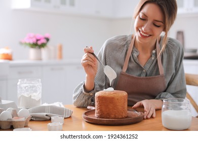 Young woman decorating traditional Easter cake with glaze in kitchen. Space for text - Powered by Shutterstock