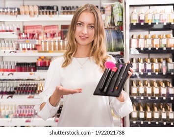 Young Woman Demonstrating Kit Of Makeup Brushes In Cosmetics Store