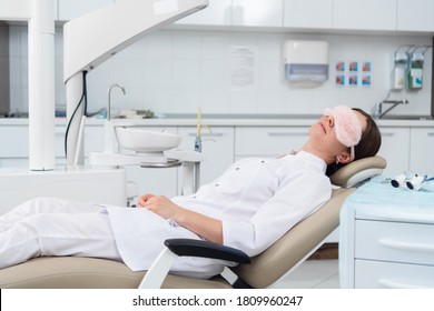 A Young Woman, A Dentist Or An Intern, Rests On The Chair In The Dentist's Office In A Very Relaxed Pose.