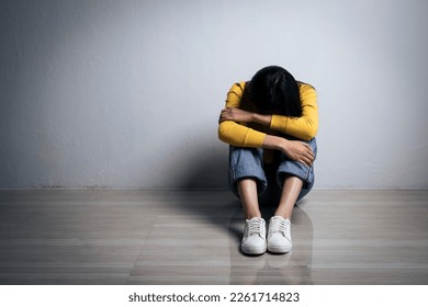 Young woman depression holding her head in her hands, knees up, Sad female sitting alone in empty room. - Powered by Shutterstock