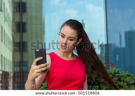 Young woman in der dress making selfie on the street