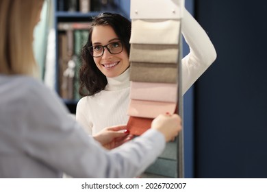 Young Woman Designer Is Talking To Saleswoman And Is Choosing Fabrics For Curtains From Textile