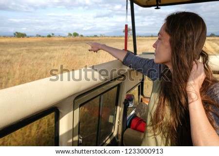 Young woman discover african nature by car Tanzania safari Point with finger
