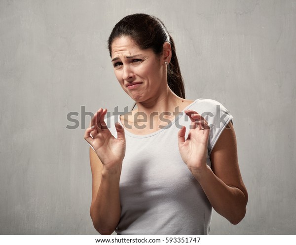 Young woman disgusted squeamishness over gray\
wall background