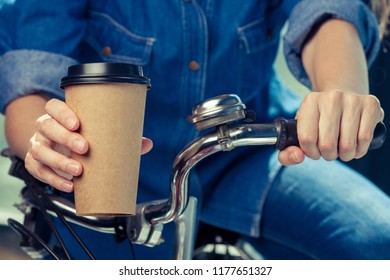 Young woman with disposable coffee cup and bike. Youth, modern lifestyle. Streets of Amsterdam. 
