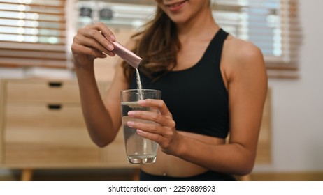 Young woman dissolving collagen powder in glass of water, preparing healthy supplement after exercise - Shutterstock ID 2259889893