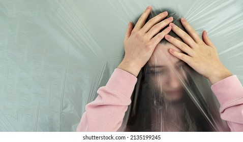 Young Woman With Distorted Face Behind Plastic Film Grabs Her Head, Because Of Headache, The Transparent Plastic Film Represents The Altered Perception And The Dull Pain, Copy Space